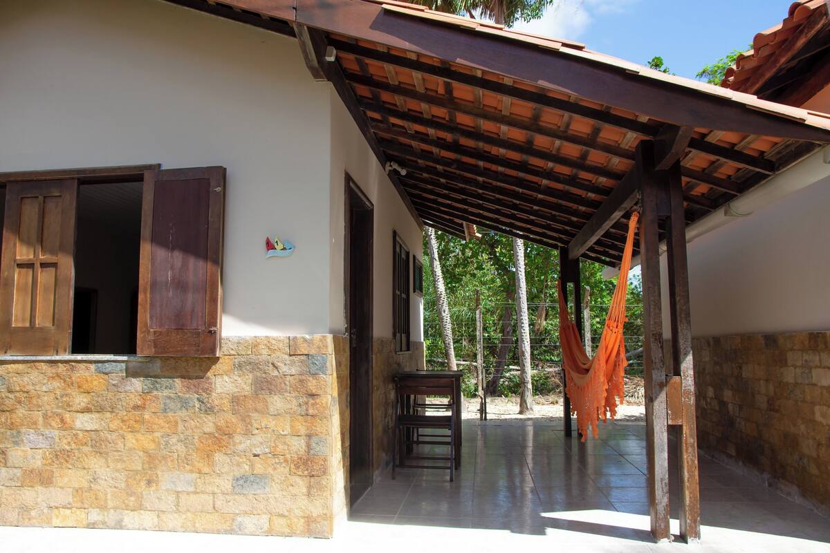 A covered outdoor area with a stone wall, a wooden table, and a hammock.
