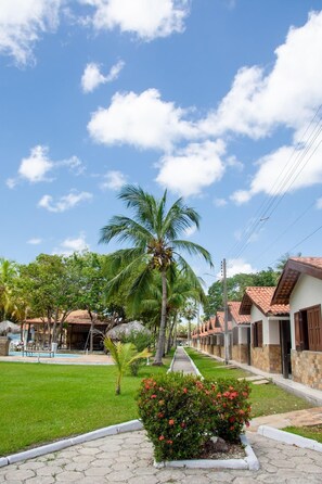 A residential area with houses, a palm tree, and a well-maintained lawn. - Pousada Orla Náutica (Barreirinhas)