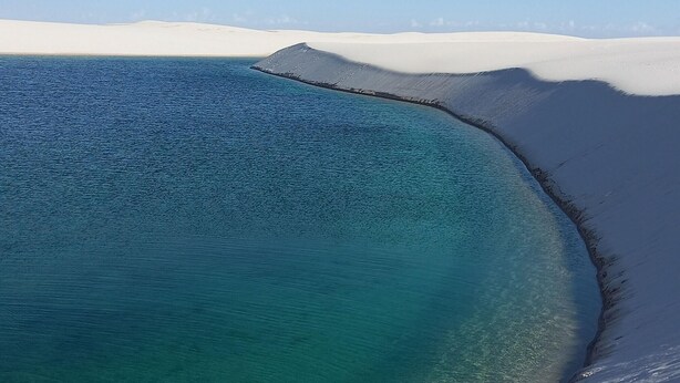 Un paisaje costero con dunas de arena blanca y un mar azul cristalino.
