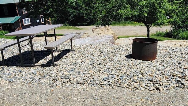 A gravel area with picnic tables and a metal planter.