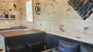 A modern kitchen with wooden walls, a central island, bar stools, and a leather sofa.