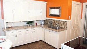 A kitchen with white cabinets, a granite countertop, a built-in sink, and a backsplash with a mosaic tile design. - Smooth Rock Falls Countryside Comfortable and Stunning 4 bedroom Spacious House (Smooth Rock Falls)