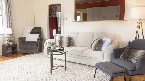 A living room with a sofa, armchairs, a coffee table, and a lamp. There is a mirror on the wall and a door leading to another room. - Smooth Rock Falls Countryside Comfortable and Stunning 4 bedroom Spacious House (Smooth Rock Falls)