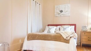 A neatly made bed with a red headboard, white bedding, and decorative pillows, including one with a deer design. - Smooth Rock Falls Countryside Comfortable and Stunning 4 bedroom Spacious House (Smooth Rock Falls)