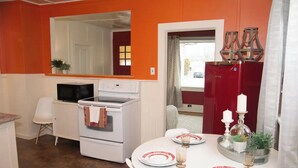 A compact kitchen with white appliances, a dining table set for two, and a red refrigerator. - Smooth Rock Falls Countryside Comfortable and Stunning 4 bedroom Spacious House (Smooth Rock Falls)