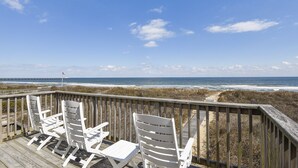 A wooden deck with white chairs overlooking a beach and ocean. - Lawrence, Ships Watch Community in Duck, NC (Duck)
