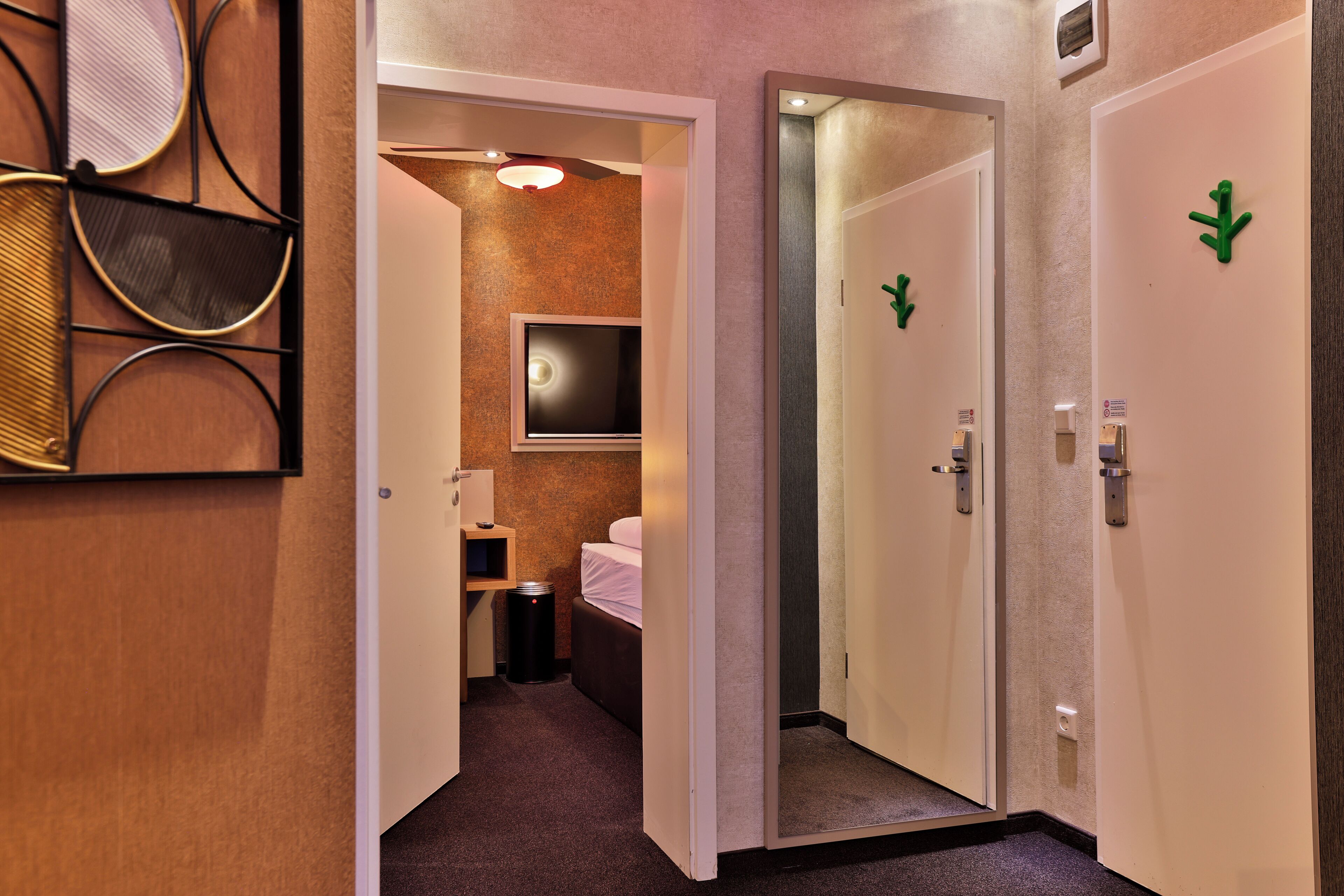 Ein Hotelkorridor mit einem Bett, einem Mülleimer und einem Fernseher in einem Zimmer.