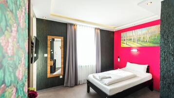 Ein Hotelzimmer mit Bett, Spiegel, einem Fenster mit Vorhängen und einem Bild an der Wand.