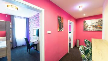 Une pièce avec un mur rose, un bureau avec un ordinateur, une chaise et un lit.