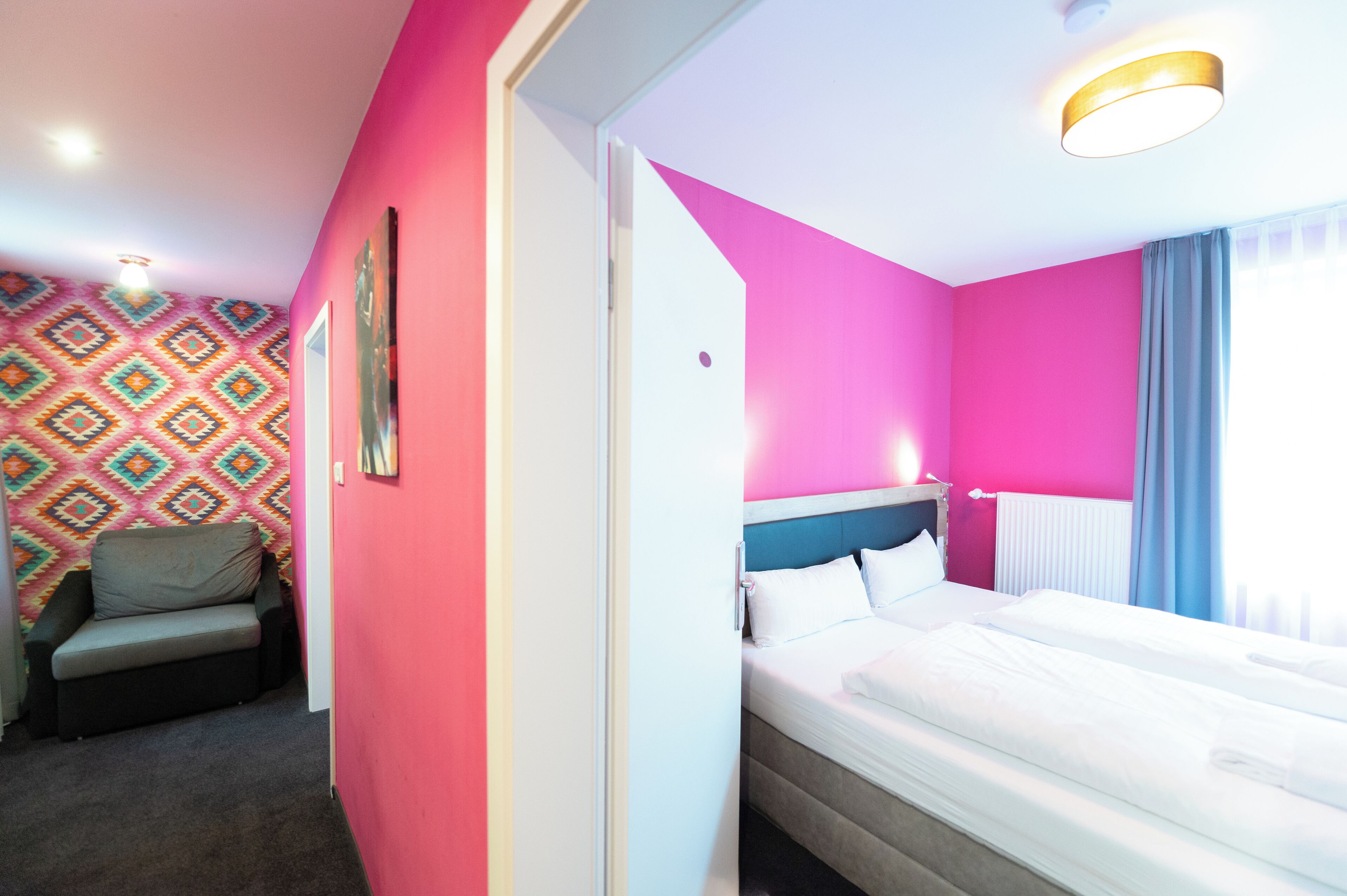 Una habitación de hotel con una cama, un sofá y un papel tapiz estampado.