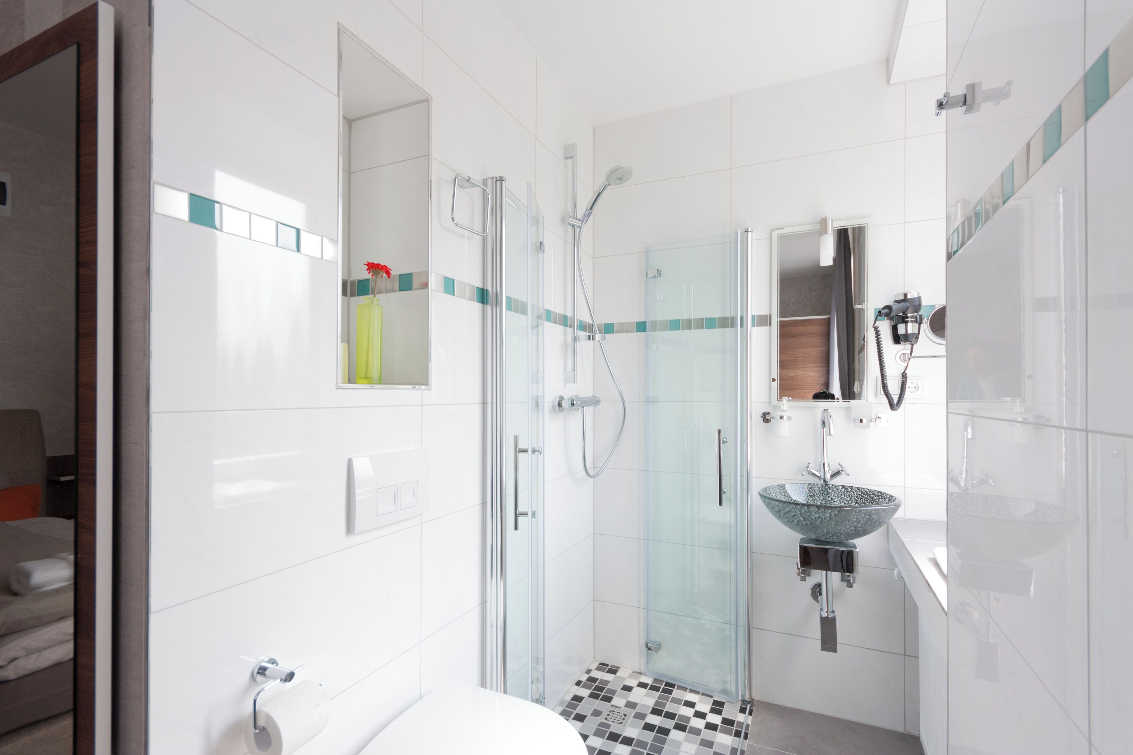A modern bathroom with a glass-enclosed shower, a glass sink, and a checkered floor.