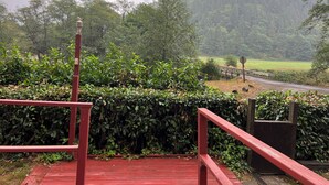 A red wooden staircase leading to a viewing platform overlooking a forested area with a road and a stop sign in the distance. - Tranquil Riverfront Retreat Near Tillamook's Best
 (Tillamook)