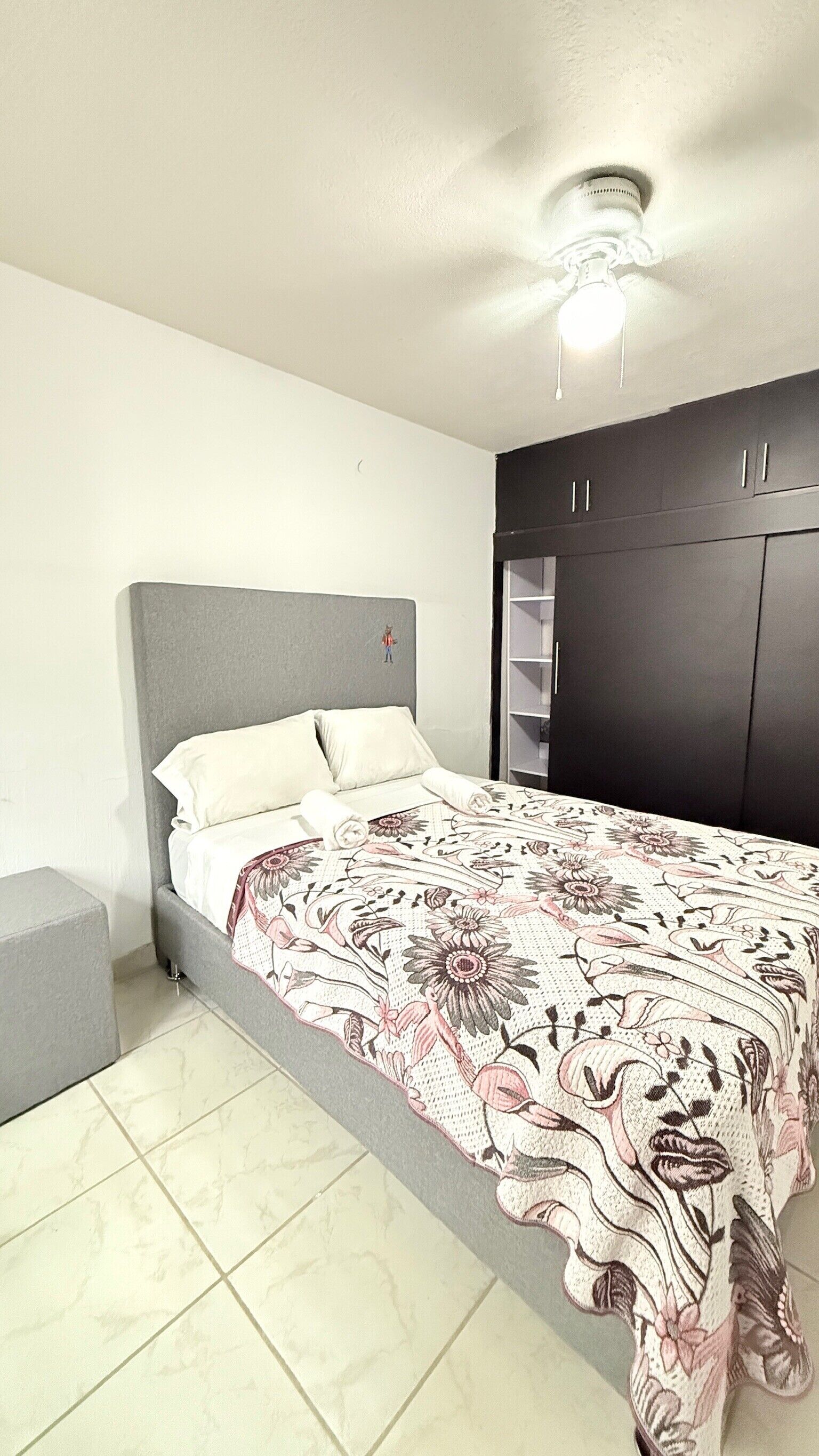 Una camera da letto con un letto, un armadio e una ventola a soffitto.
