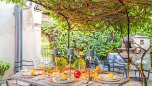 Ein Essbereich im Freien mit einem Tisch für vier Personen, umgeben von Stühlen, unter einer Pergola.