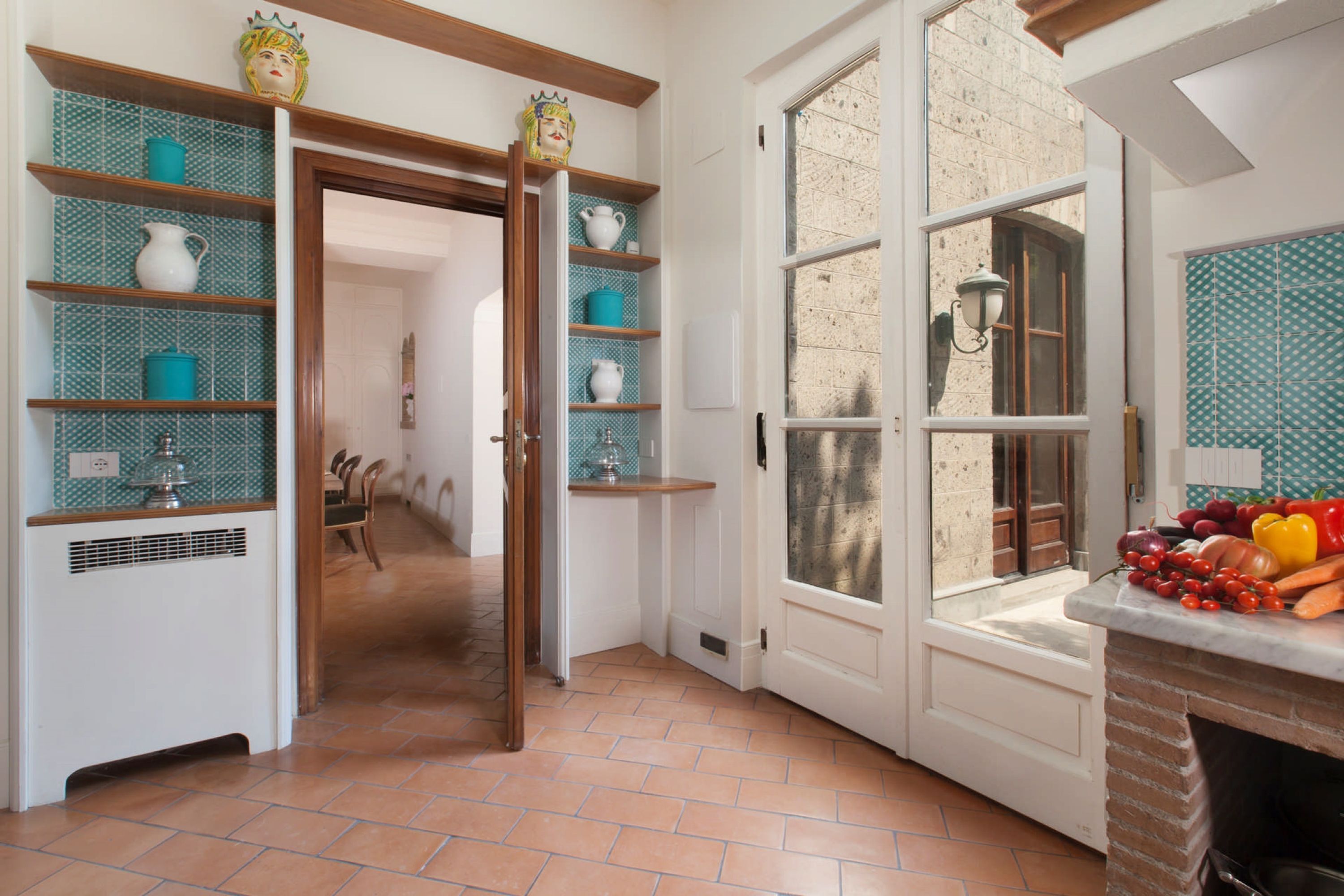 Una cocina con estantes abiertos, una ventana y una chimenea de ladrillo.