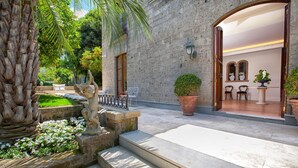 A stone building with a grand entrance, steps leading to a patio, and outdoor seating. - Villa Ebe in Sorrento (Sorrento)