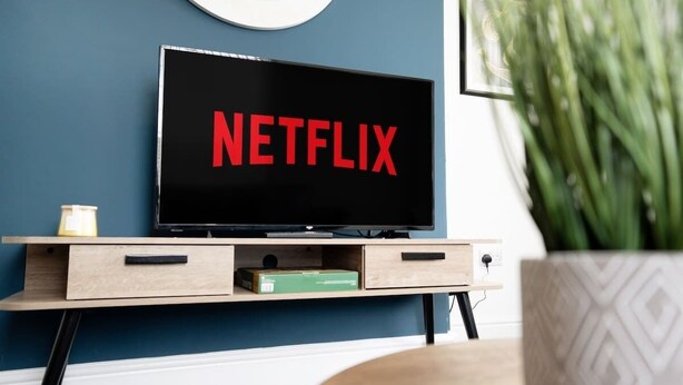 Un televisor con el logo de Netflix sobre un mueble de televisión de madera.