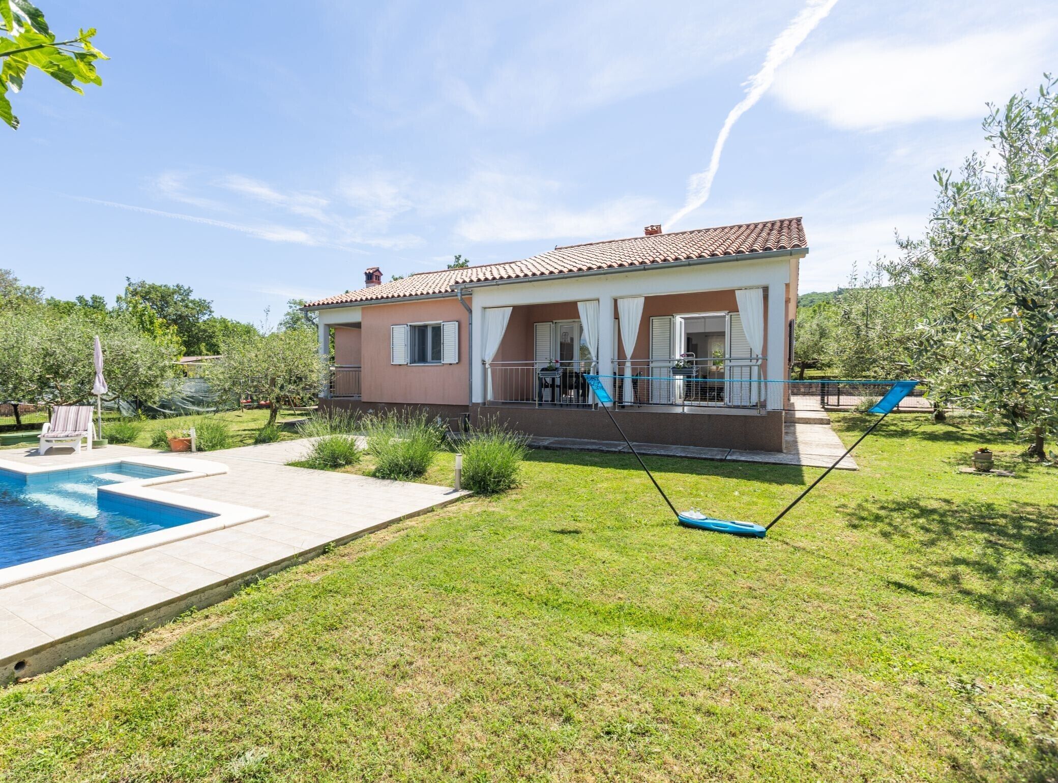 Ein zweistöckiges Haus mit Pool, überdachter Terrasse und Garten.