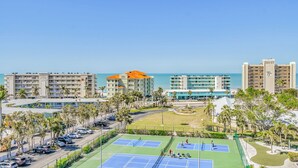 Ein Hotel an der Küste mit mehreren Gebäuden, einem Tennisplatz und einem Parkbereich.
