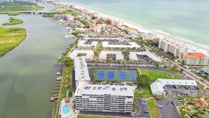 Luftaufnahme eines Hotels an der Küste mit einem Yachthafen, Strand und Tennisplätzen.