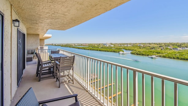 Ein Balkon mit Blick auf einen Fluss, Außenmöbel und Geländer.