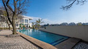 A swimming pool with a tiled edge, surrounded by a stone patio and a few lounge chairs. - ANEW Hotel & Convention Centre OR Tambo (Benoni)
