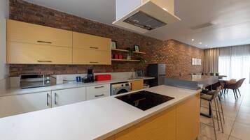 A modern kitchen with a brick wall, wooden cabinets, a built-in oven, and a bar area with stools.
