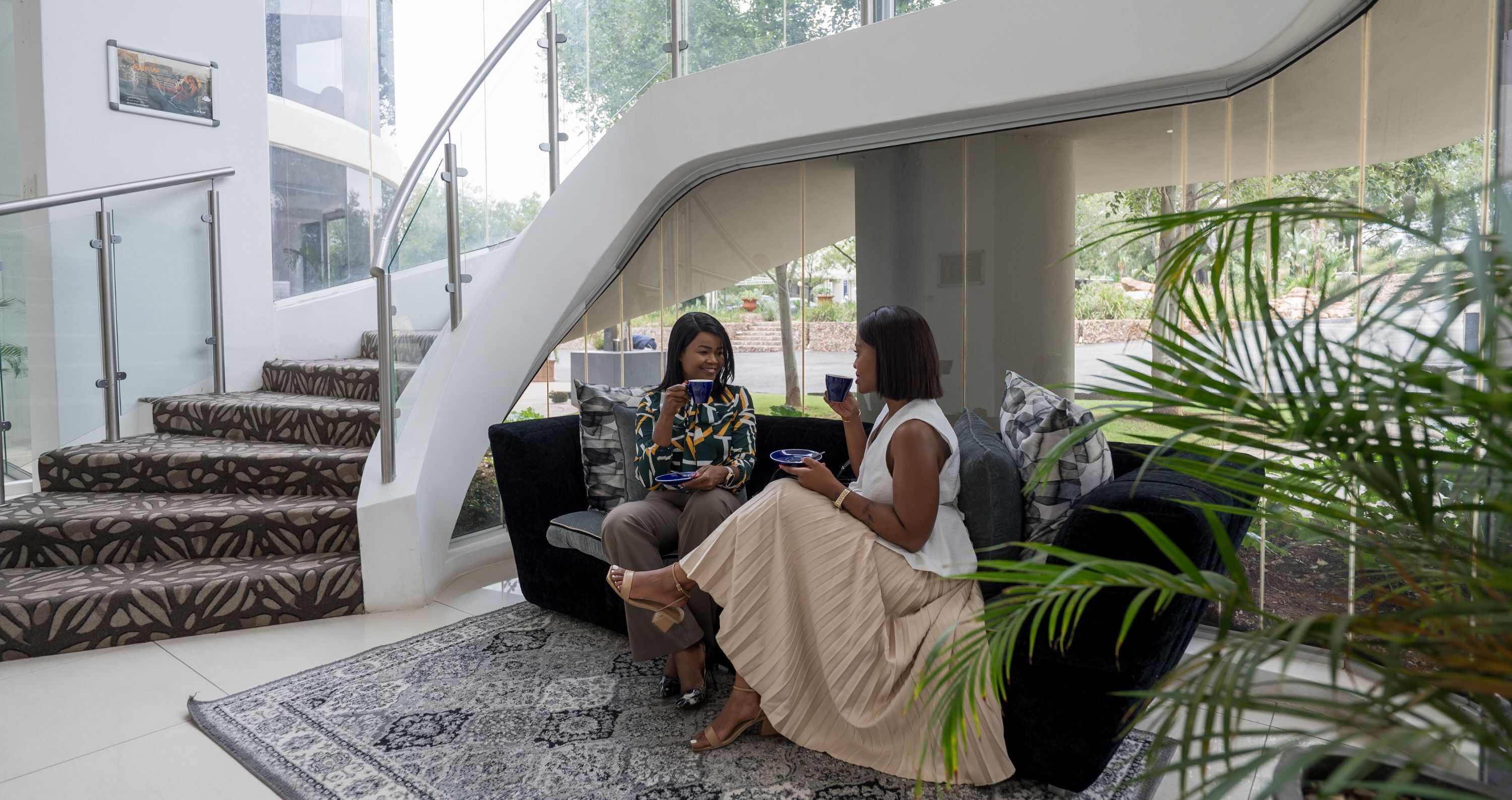 Ein modernes Interieur mit einer Treppe, einem schwarzen Sofa und einem gemusterten Teppich.