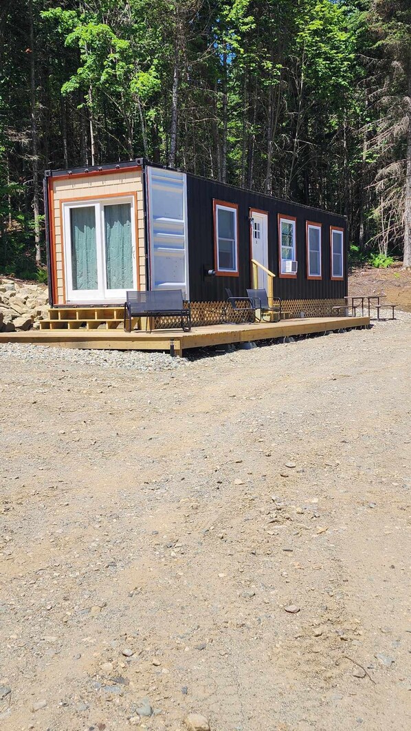 A small, single-story cabin with a front porch and a covered deck area.