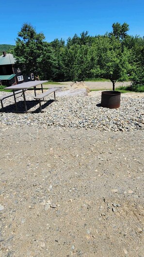 A gravel area with picnic tables and a metal planter.