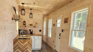 A cozy cabin interior with wooden walls, a kitchen area, and a seating area with a couch and a small table.