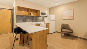 A modern kitchen with a white countertop, wooden cabinets, a microwave, and a refrigerator. - LivAway Suites Nashville- Smyrna (Smyrna)