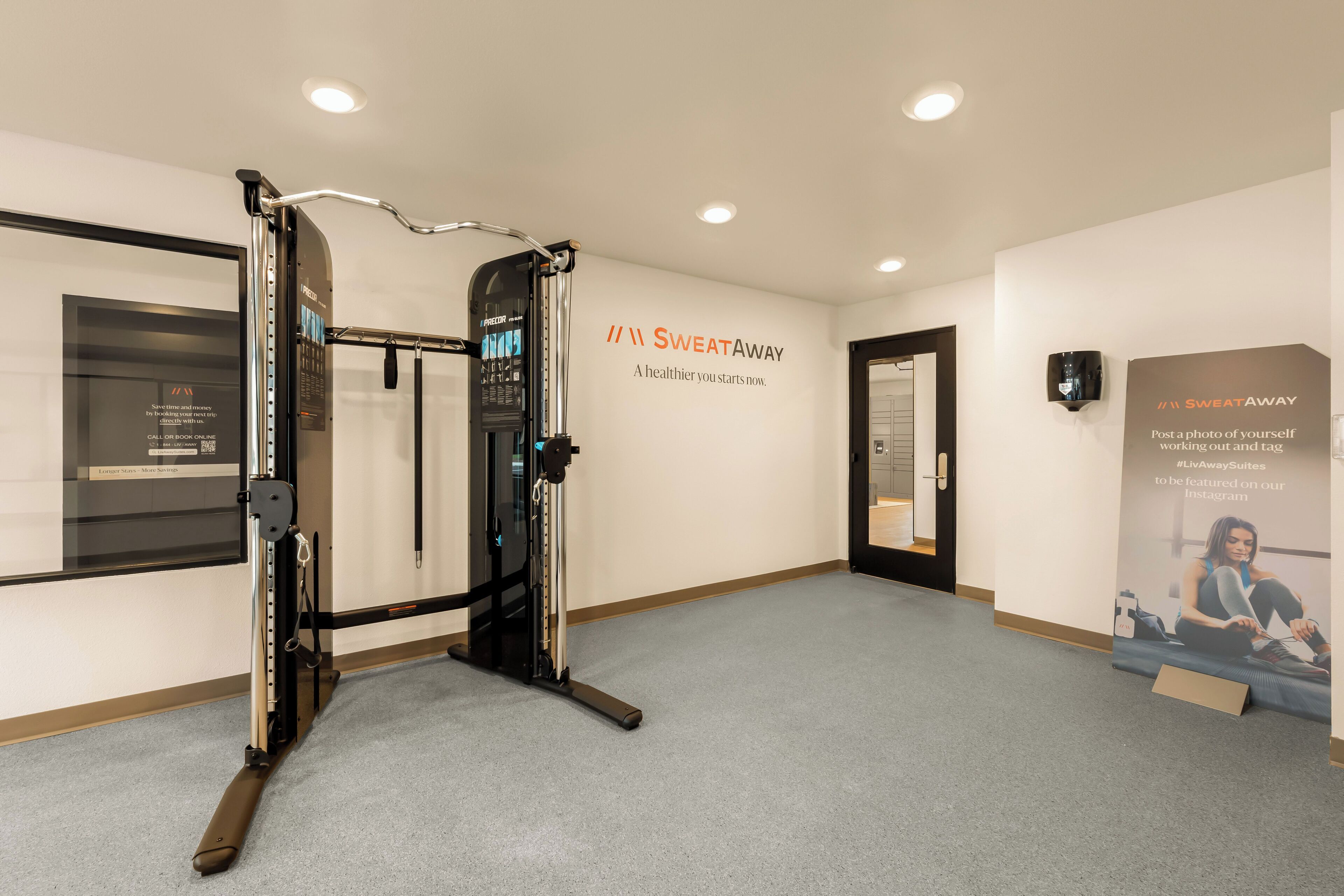 A gym with a pull-up bar, a wall-mounted screen, and a poster encouraging Instagram posts.