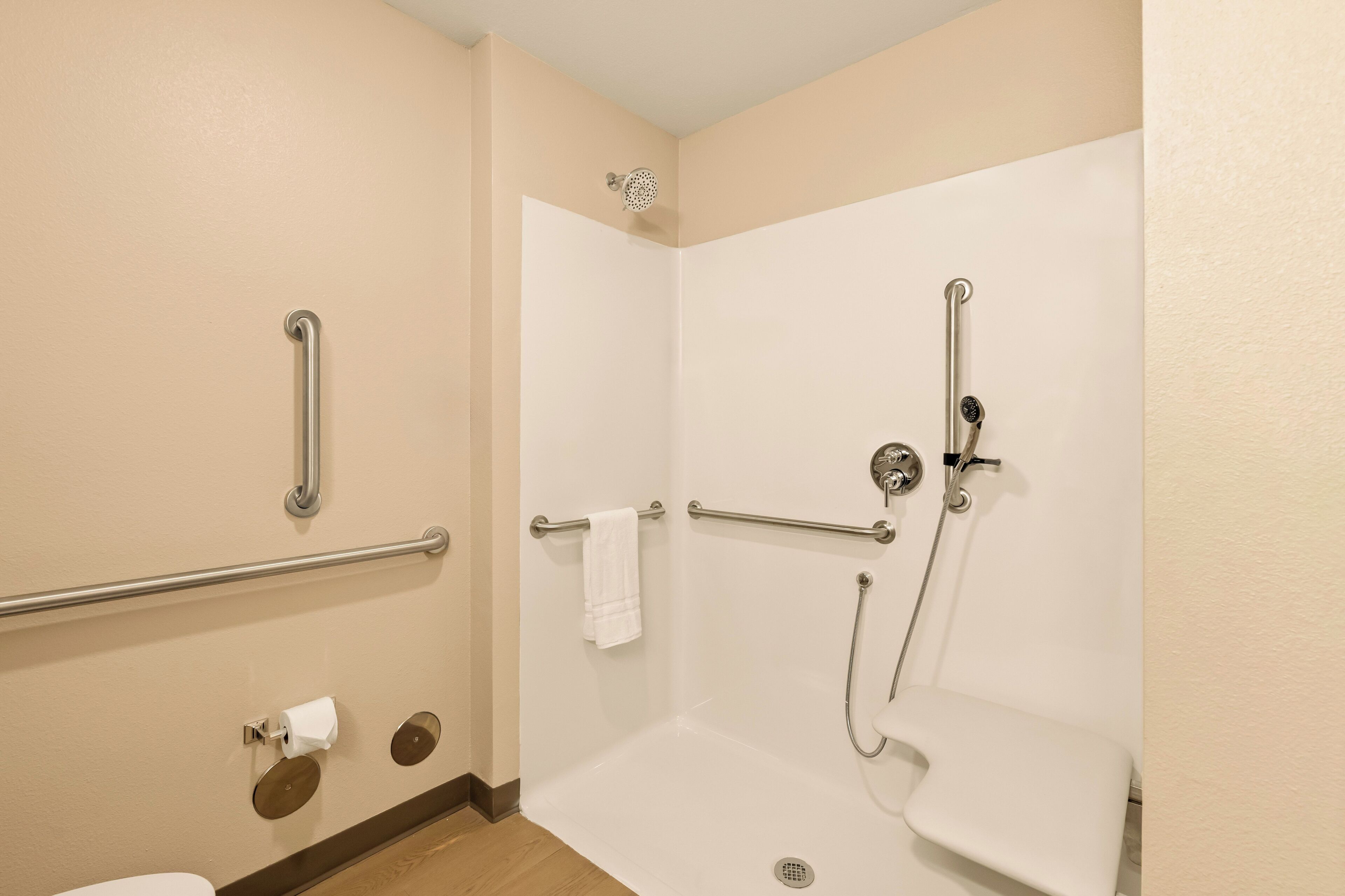 A bathroom with a walk-in shower, grab bars, a toilet, and a sink.