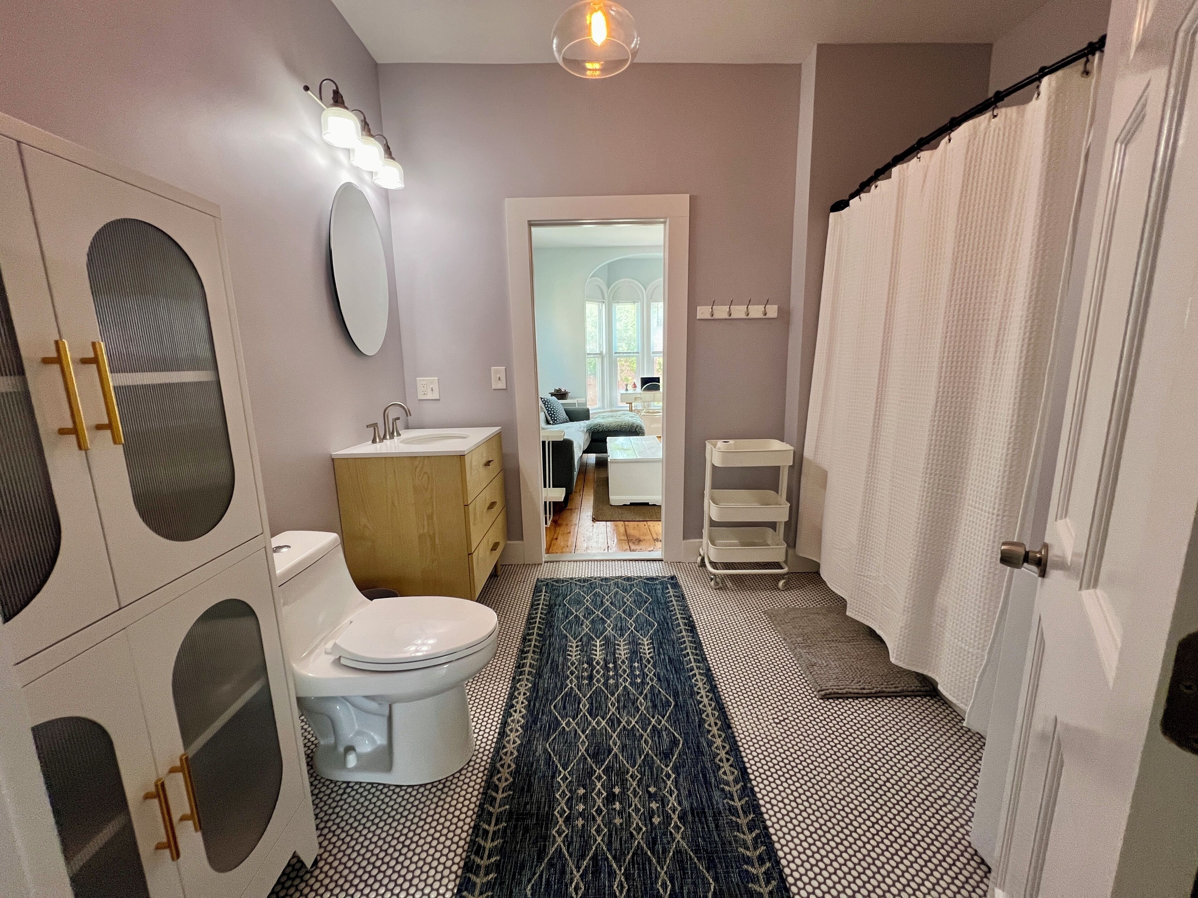 A bathroom with a toilet, sink, vanity, and a shower curtain.