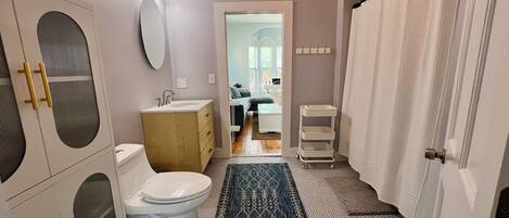 A bathroom with a toilet, sink, vanity, and a shower curtain.