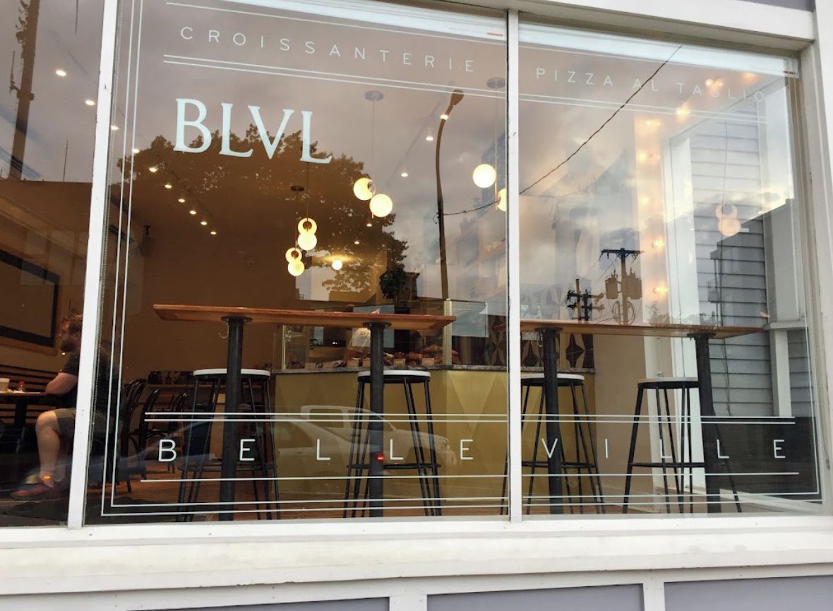 A restaurant window with 'BLV BELLE VILLE' signage, outdoor seating, and a view of the street.