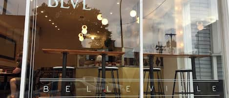 A restaurant window with 'BLV BELLE VILLE' signage, outdoor seating, and a view of the street.