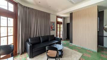 A modern living room with a black sofa, a round coffee table, and a chair. There is a large window with curtains, a door, and a wall with vertical lines.