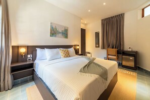 Een hotelkamer met een groot bed, nachtkastjes, een bureau en een stoel.
