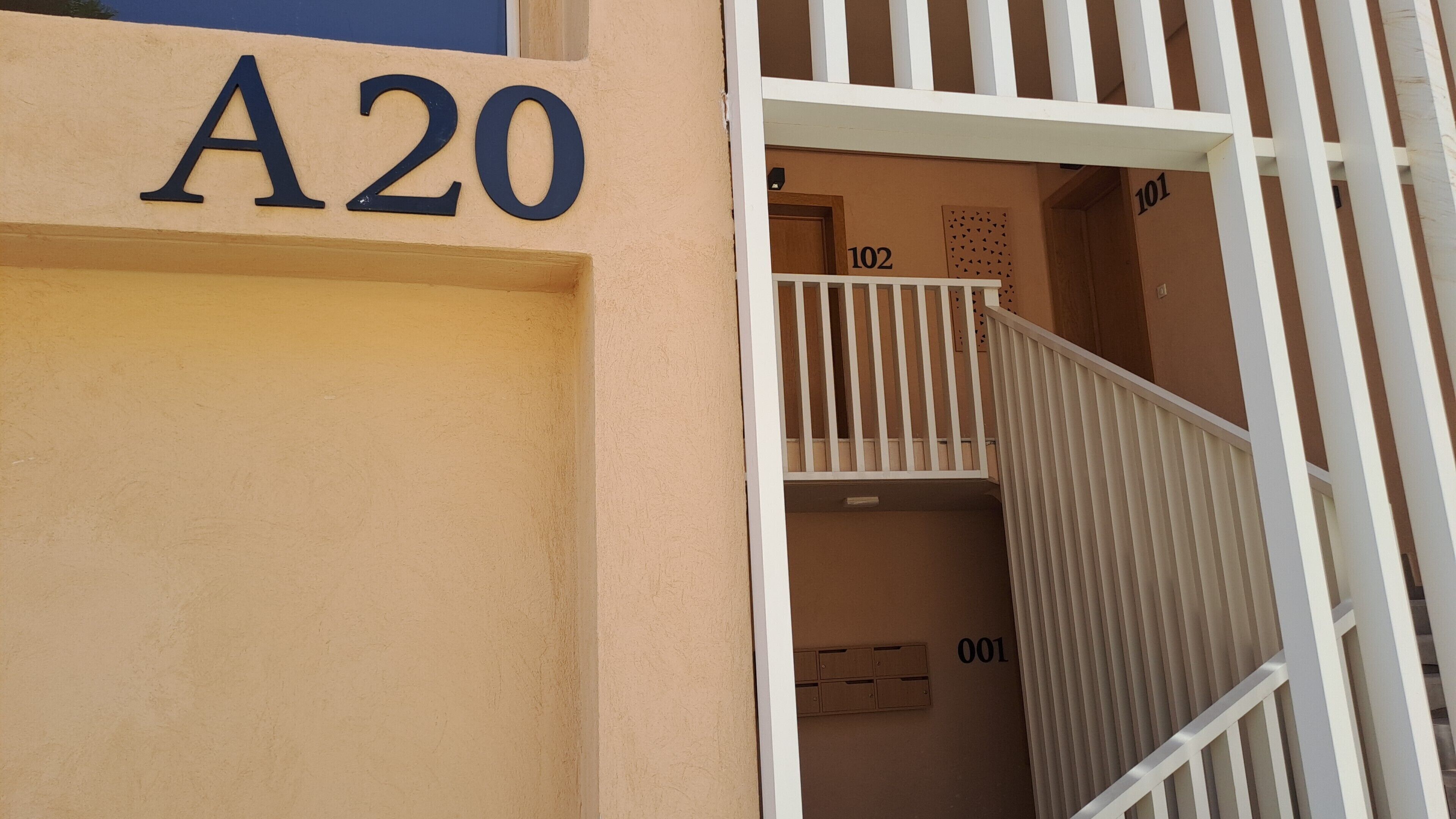 A building entrance with a beige facade and a white gate. The number 'A20' is prominently displayed above the gate.