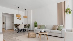 Una sala de estar moderna con comedor, que incluye un sofá, una mesa de centro y una mesa de comedor con sillas.