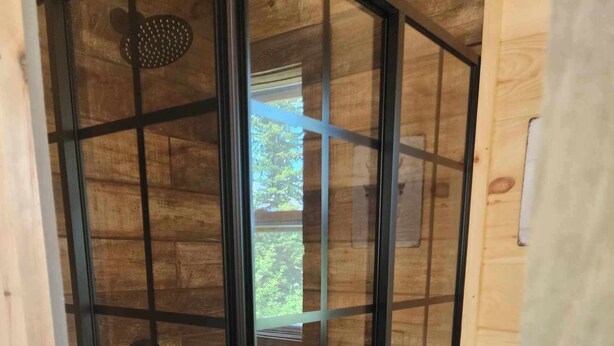 A wooden interior with a glass door leading to a balcony. - New 1 bedroom Container cabin with direct trail access (cabin 3) (Errol)