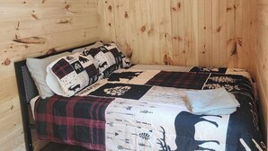 A single bed with a quilted cover, a ceiling fan, and wooden walls. - New 1 bedroom Container cabin with direct trail access (cabin 3) (Errol)