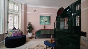 A living room with a black sofa, a round table, a green cabinet, and a painting on the wall.