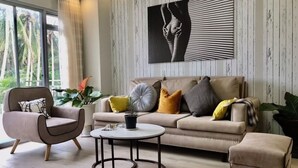 Un salon moderne avec un canapé beige, une table basse ronde et une grande œuvre d’art abstraite accrochée au mur.
