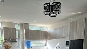 Une cuisine moderne avec des meubles de couleur bois clair, un réfrigérateur noir et deux tabourets de bar noirs.