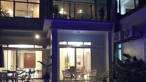 Une maison moderne à deux étages dotée d’une piscine illuminée par des lumières bleues.