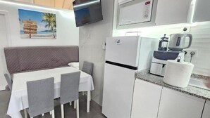 Een kleine keuken met een koelkast, magnetron en koffiezetapparaat.