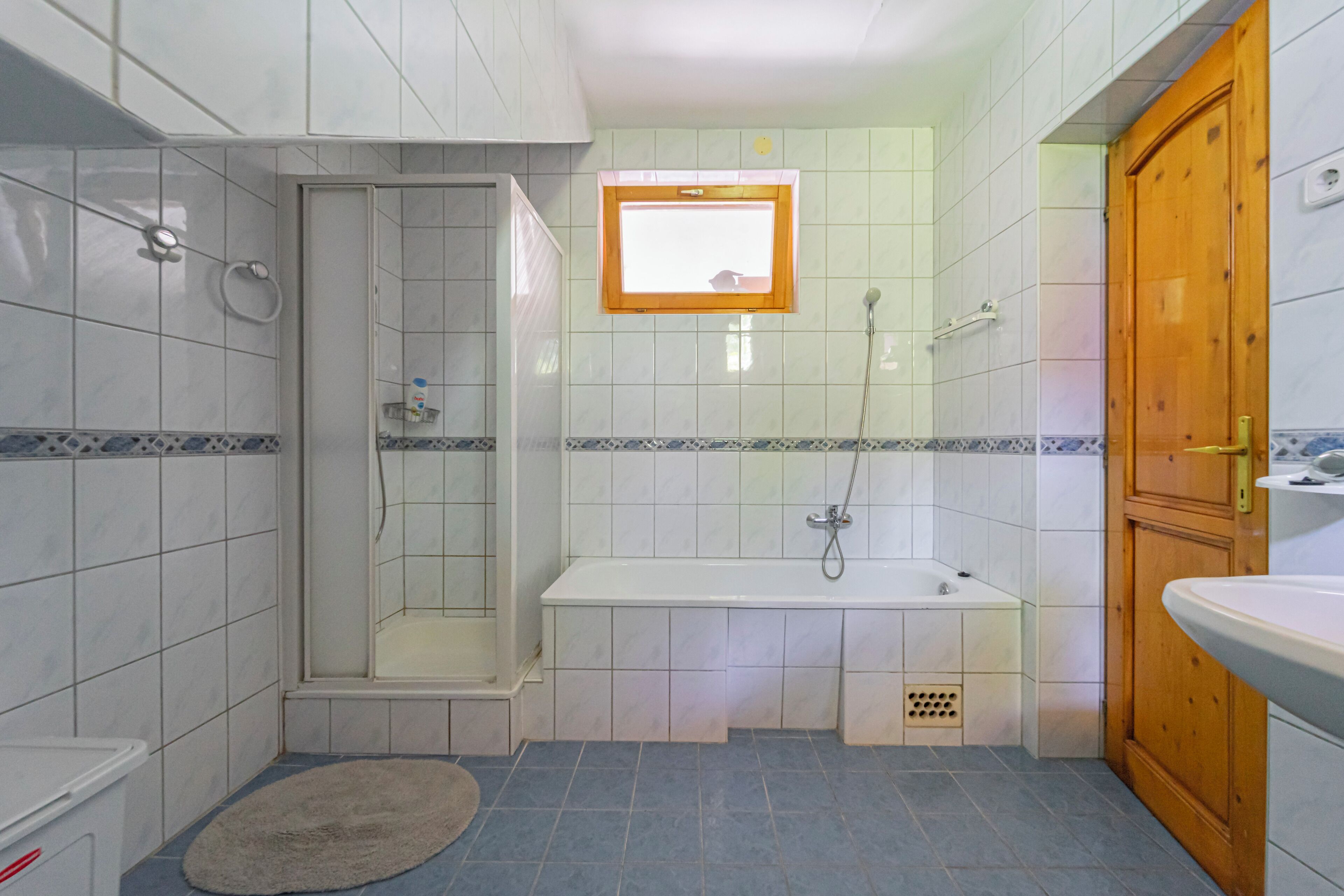 A bathroom with a shower, bathtub, and a wooden door.